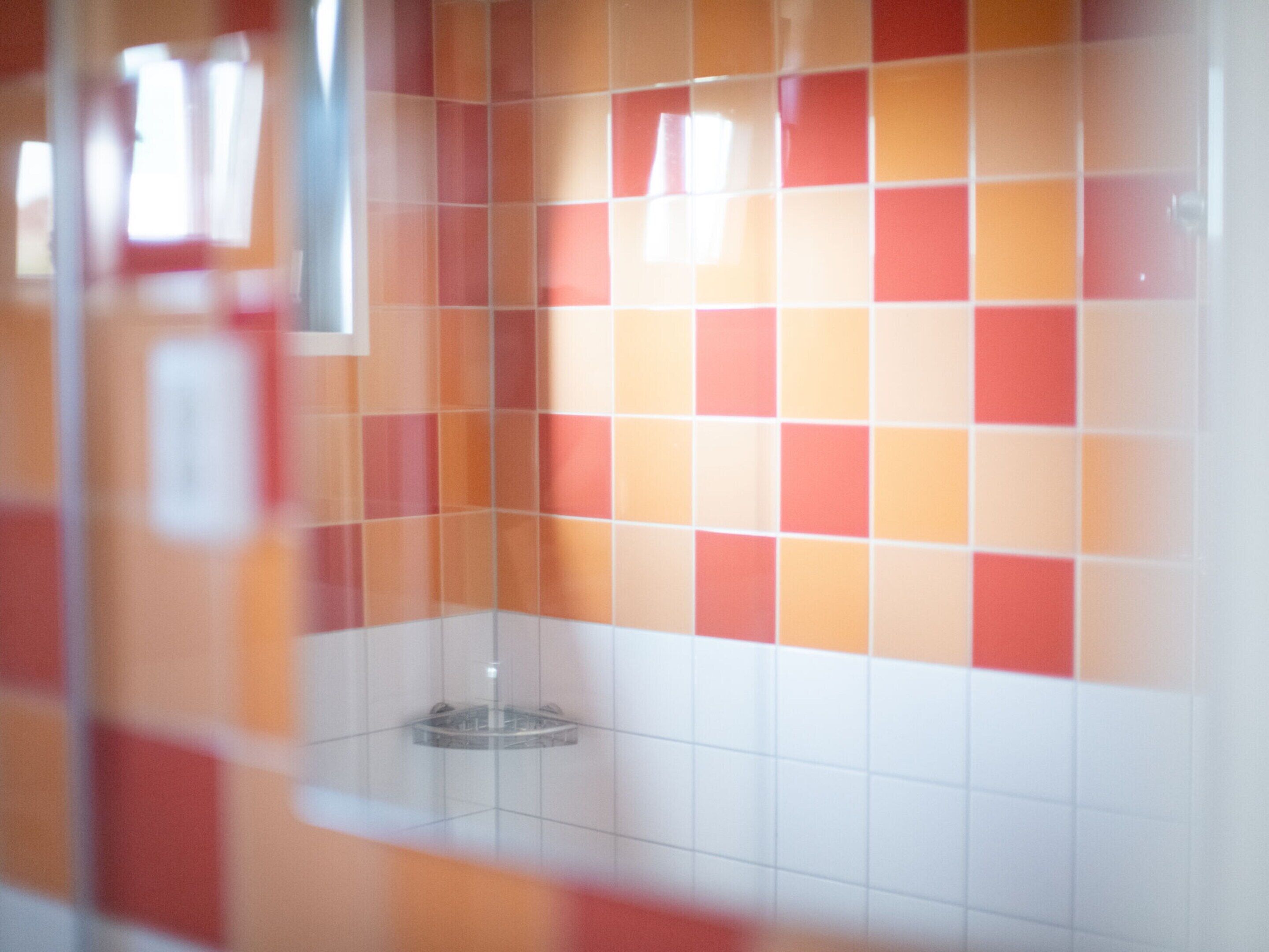 Una pared de azulejos con un diseño de baldosas anaranjadas y blancas.