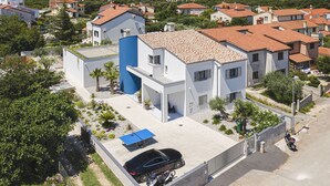A residential area with modern houses, a blue-roofed building, and a clear view of the sea. - Villa in Stinjan With Pool and Sea View (Pula)