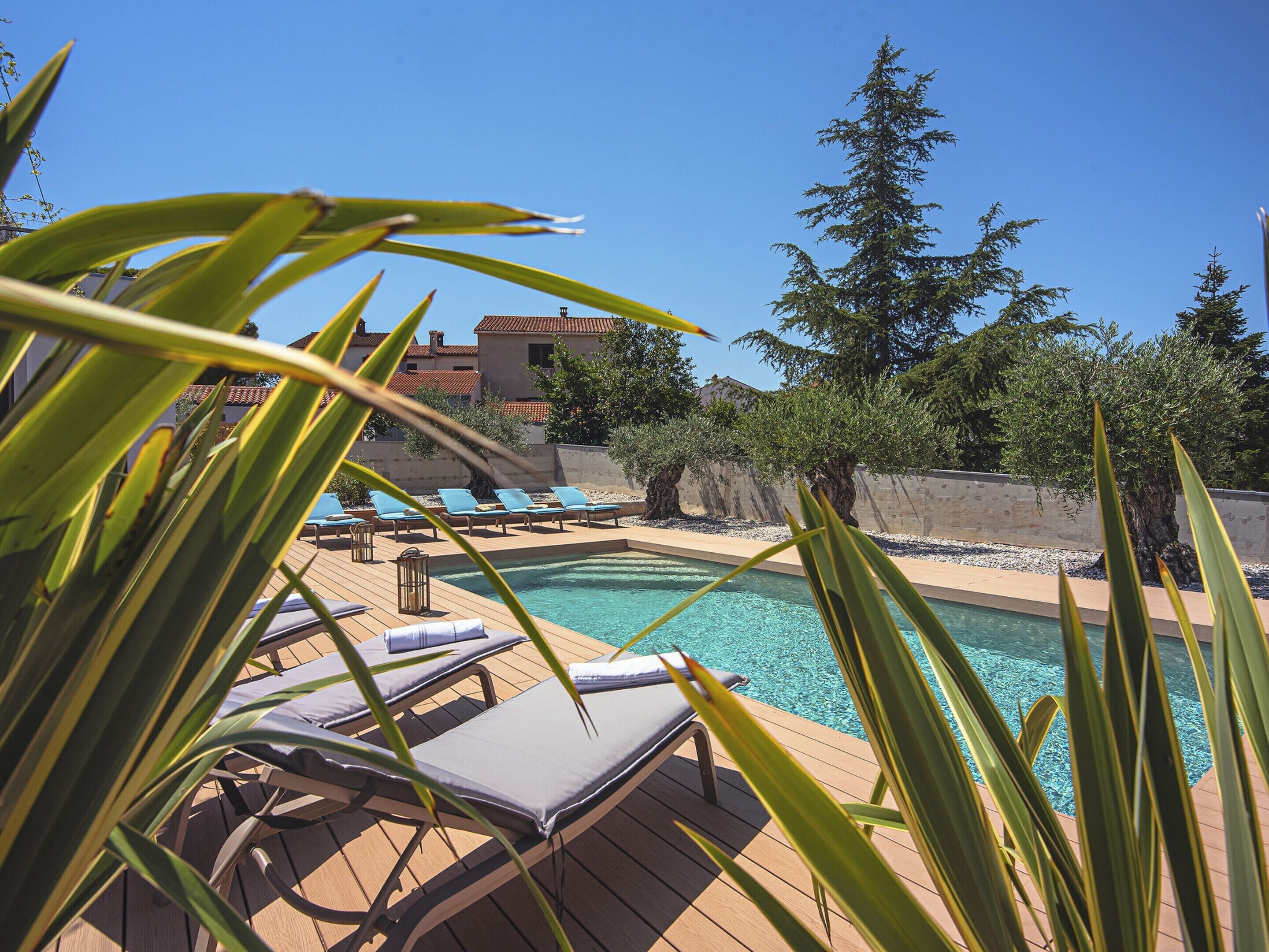 Un espace piscine avec des chaises longues et une terrasse en bois.