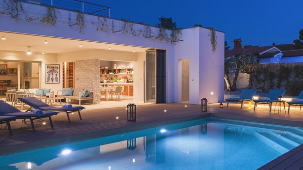 A modern outdoor pool area with lounge chairs and a dining area. - Villa in Stinjan With Pool and Sea View (Pula)