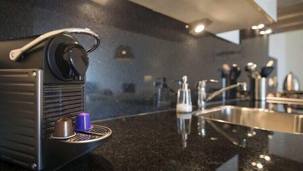 Une cuisine moderne équipée d’une machine à café, d’un évier et d’un plan de travail.