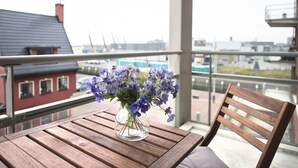 Un balcon avec une table en bois et un vase rempli de fleurs violettes.