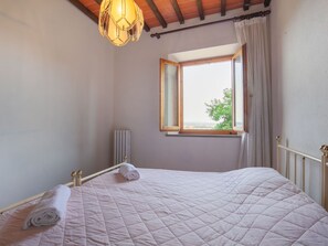 A bedroom with a bed, a window, a radiator, and a hanging light fixture. - Spacious Tuscany Retreat (Gambassi Terme)