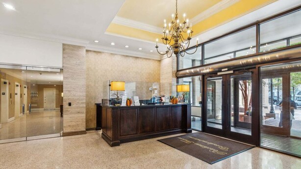 A hotel lobby with a reception desk, a chandelier, and a glass door entrance. - Downtown retreat on iconic Peachtree w/ balcony (Atlanta)