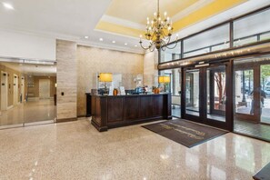 Et hotellobby med en receptionsdisk, en lysekrone og en glasklarlugt.