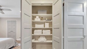 A walk-in closet with multiple shelves, a ceiling fan, and a bed with a patterned rug. - Downtown retreat on iconic Peachtree w/ balcony (Atlanta)