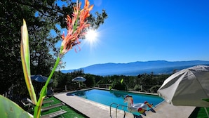 A pool area with a view of mountains, lounge chairs, and umbrellas. - Apartment With Pool, Rignano (Rignano sull'Arno)