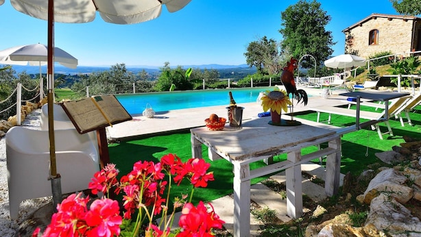 A poolside area with a view of the landscape, outdoor seating, and a rooster statue. - Apartment With Pool, Rignano (Rignano sull'Arno)