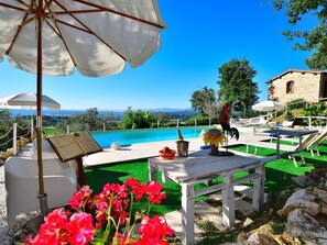 A poolside area with a view of the landscape, outdoor seating, and a rooster statue. - Apartment With Pool, Rignano (Rignano sull'Arno)