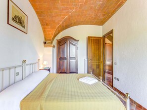 A bedroom with a bed, a wooden wardrobe, a door, and a framed picture on the wall. - Sun-kissed Apartment With Garden (Gambassi Terme)