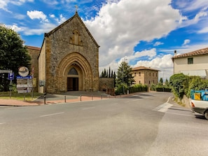 Une église en pierre avec une entrée centrale en forme d’arc, un panneau indiquant un parking et des panneaux de signalisation.