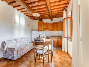 Una cocina acogedora con armarios de madera, una mesa de comedor con sillas, un sofá y una ventana.