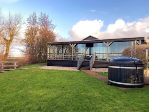 A modern house with a large glass window, a wooden deck, and a barbecue grill. - Cottage in Paesens Near Wadden Sea (Paesens)