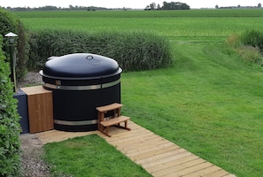 A large outdoor grill with a wooden bench and a pathway leading to it. - Cottage in Paesens Near Wadden Sea (Paesens)
