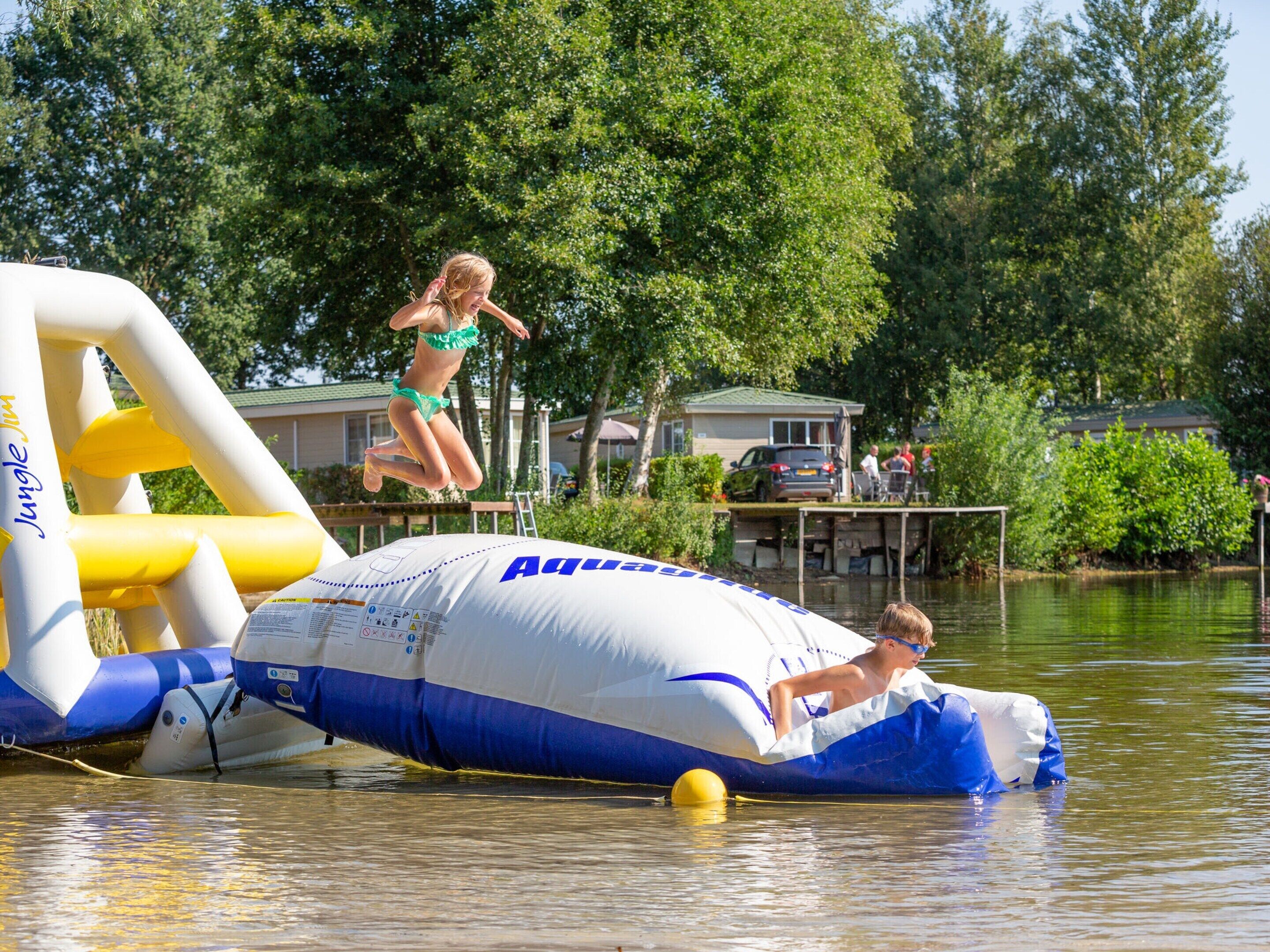 A water body with inflatable structures, including a large blue and white inflatable and a yellow and white inflatable.