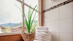 A bathroom with a window, a woven plant pot, and stacked towels. - Apartment in Hainzenberg Near Ski Lift (Hainzenberg)