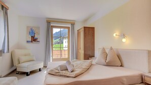 A hotel room with a large bed, a chair, a wardrobe, and a painting on the wall. - Apartment in Hainzenberg Near Ski Lift (Hainzenberg)
