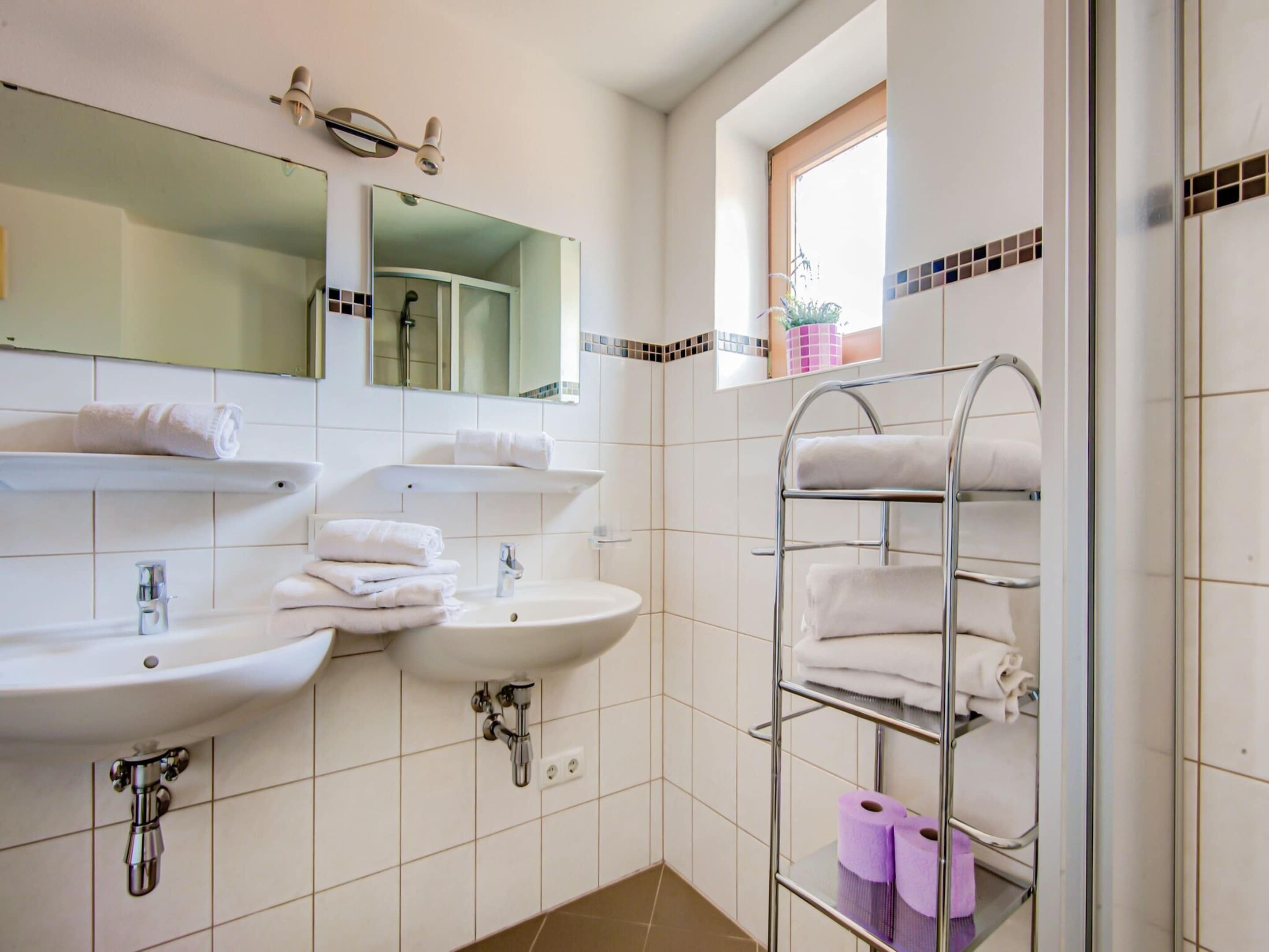 A bathroom with two sinks, a mirror, and a towel rack.