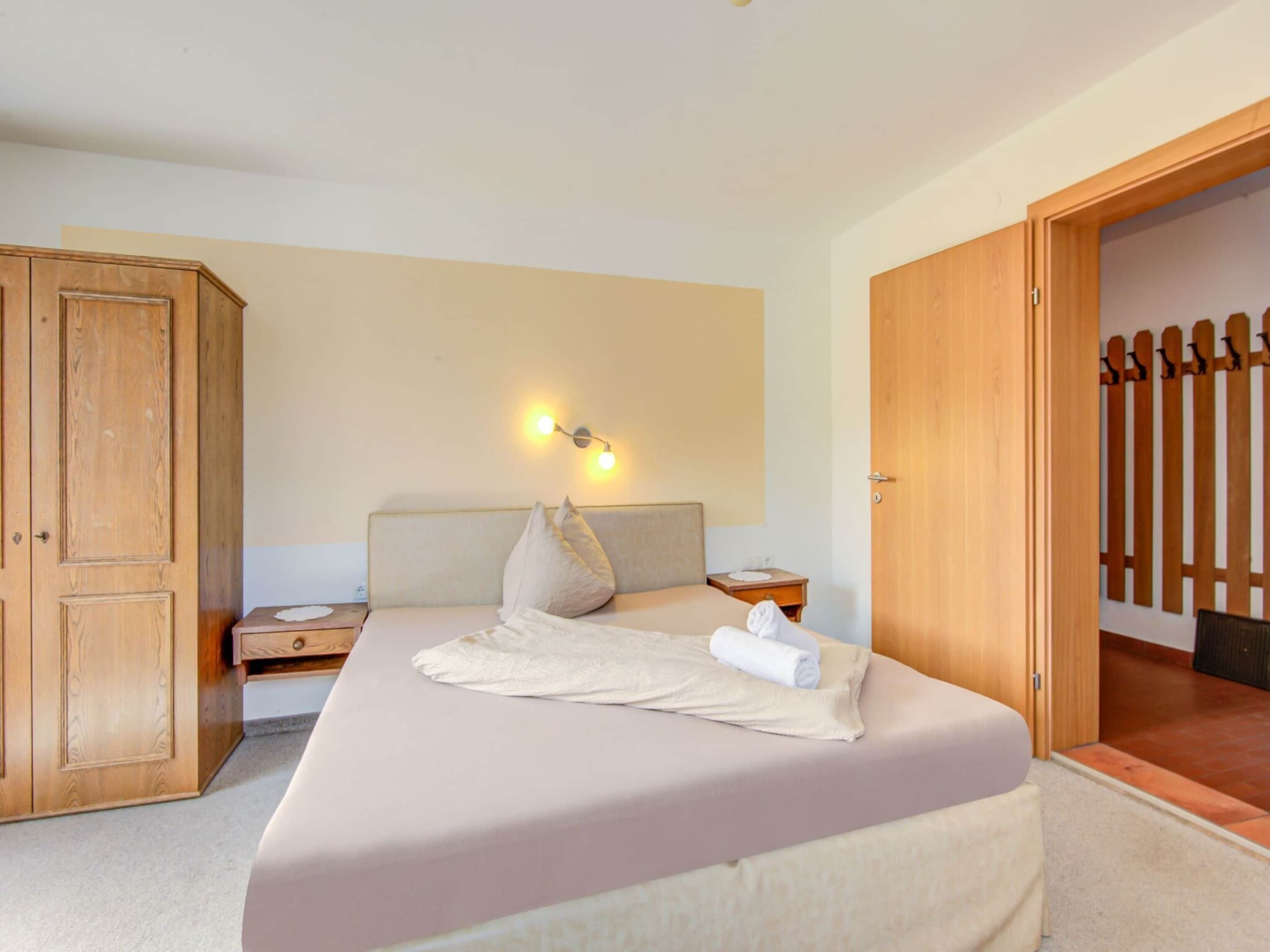 Une chambre à coucher avec un lit, une armoire en bois et une table de chevet.