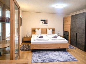 A modern bedroom with a wooden bed, two nightstands, a glass-enclosed wardrobe, and a marble-patterned rug. - Country House in Seefeld Near Ski Resort (Seefeld in Tirol)