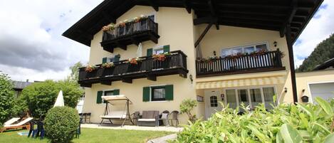 A two-story building with balconies, outdoor seating, and a well-maintained garden.