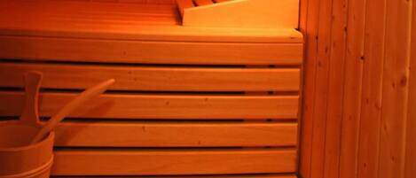 A sauna with wooden benches and a bucket.