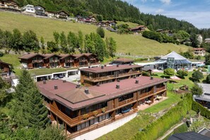 A multi-story building with balconies, a covered outdoor area, and a view of a mountainous landscape.