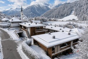 A snow-covered building with a prominent tower, surrounded by a mountainous landscape and a frozen lake. - Tranquil Mountain Chalet for 8 (Wald im Pinzgau)