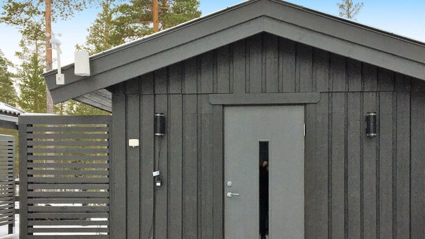 A small, dark-colored wooden shed with a door and a window. - 5 Person Holiday Home in Sarna (Sarna)