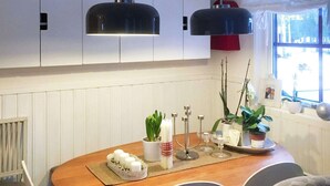 A dining area with a wooden table, white chairs, potted plants, candles, and pendant lights. - 5 Person Holiday Home in Sarna (Sarna)