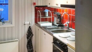 A compact kitchen with a sink, stove, and coffee maker. - 5 Person Holiday Home in Sarna (Sarna)