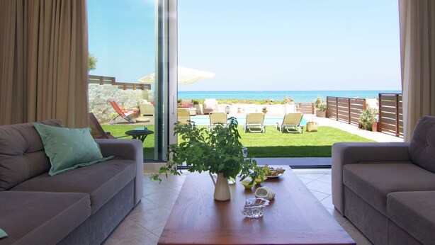 Un salon doté d’une grande porte-fenêtre coulissante donnant sur un balcon avec vue sur la mer.