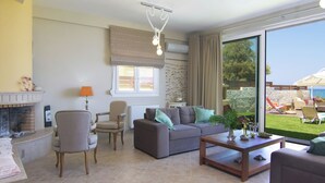 Un salon avec une cheminée, un canapé, une table basse et une vue sur l’extérieur.