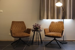 Two comfortable chairs flank a small table with a floral arrangement.