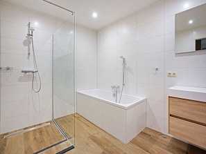 Bathroom features a glass-enclosed shower, bathtub, and wooden vanity with a mirror.