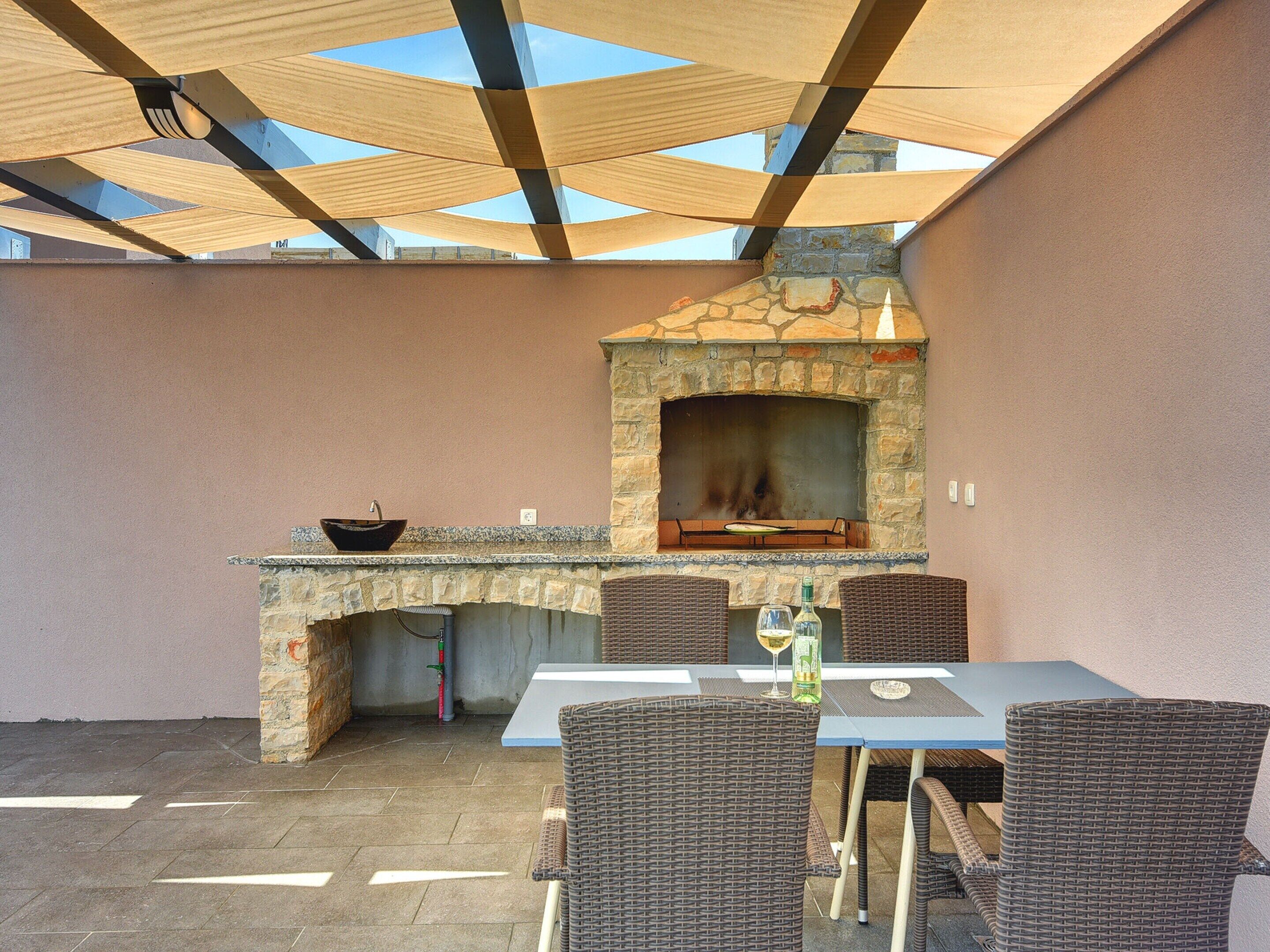 An outdoor patio with a stone fireplace, wicker furniture, and a table with a bottle and glass.