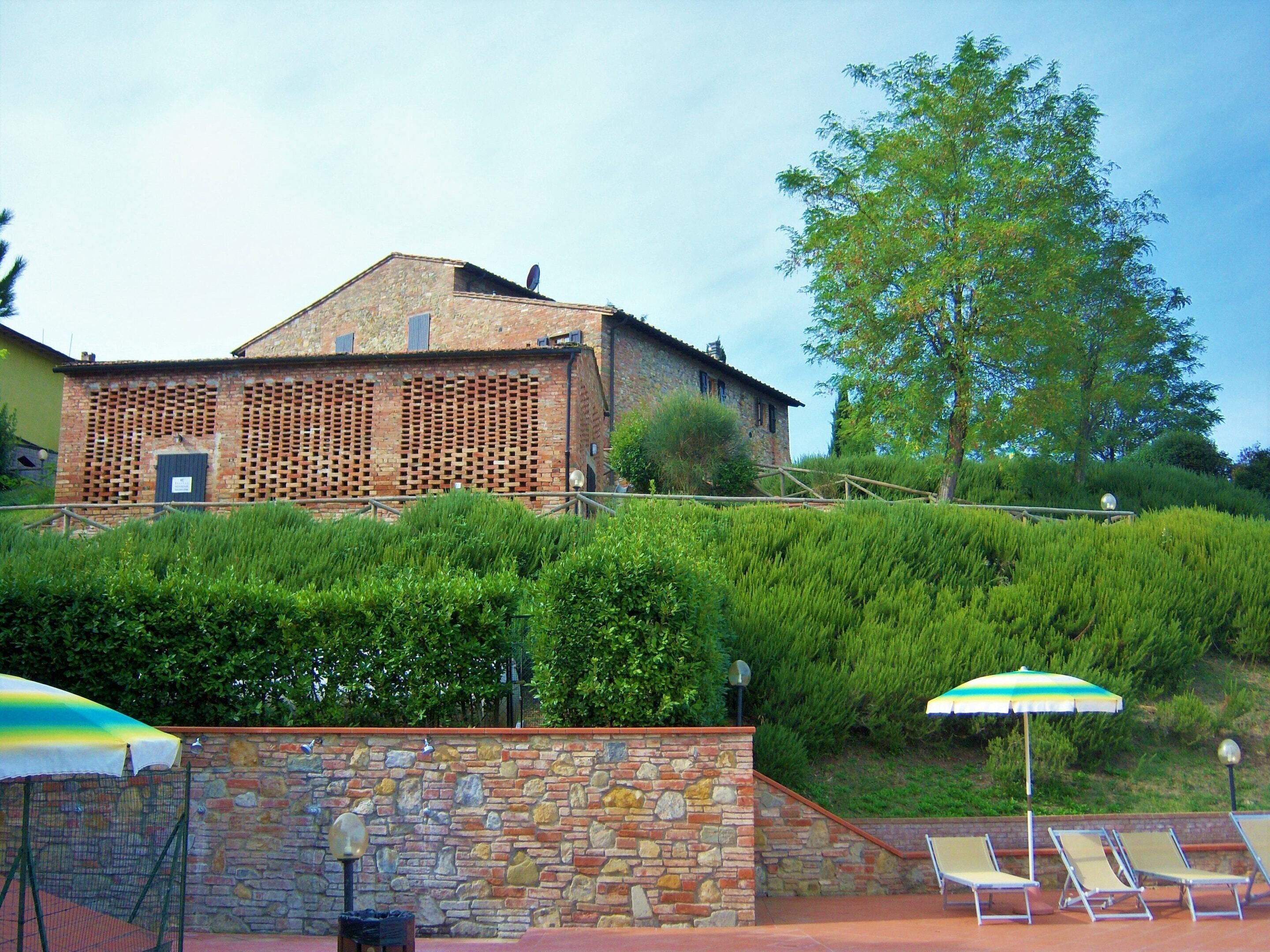 A building with a stone facade, a wooden fence, and a large tree in the background.