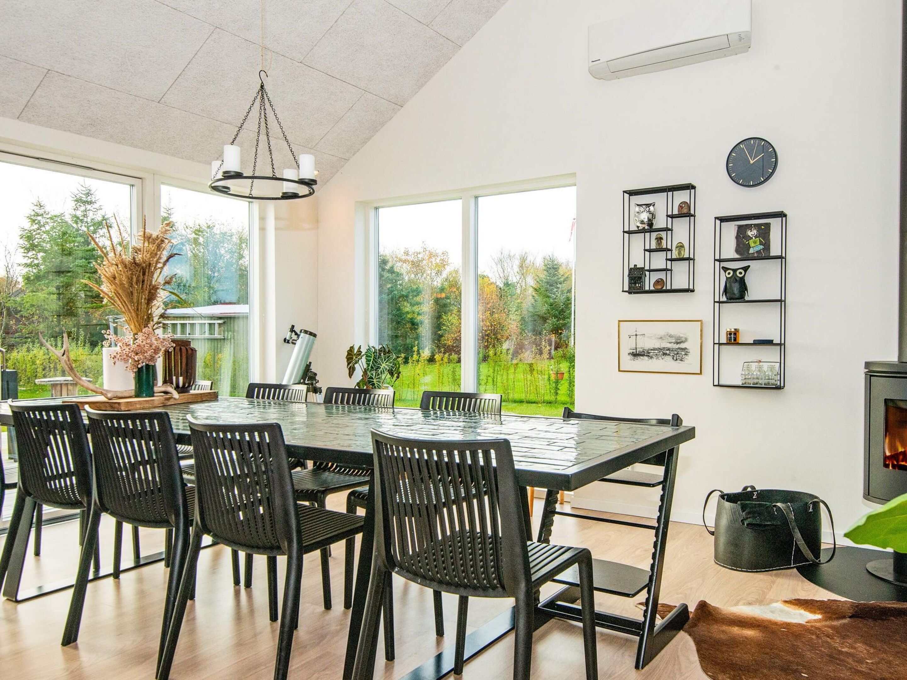 A modern dining area with a large table and chairs, a fireplace, and a view of the outdoors.