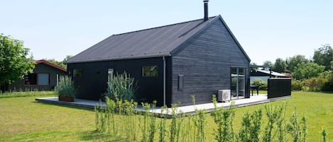 Una casa moderna con fachada oscura, techo inclinado y chimenea visible.
