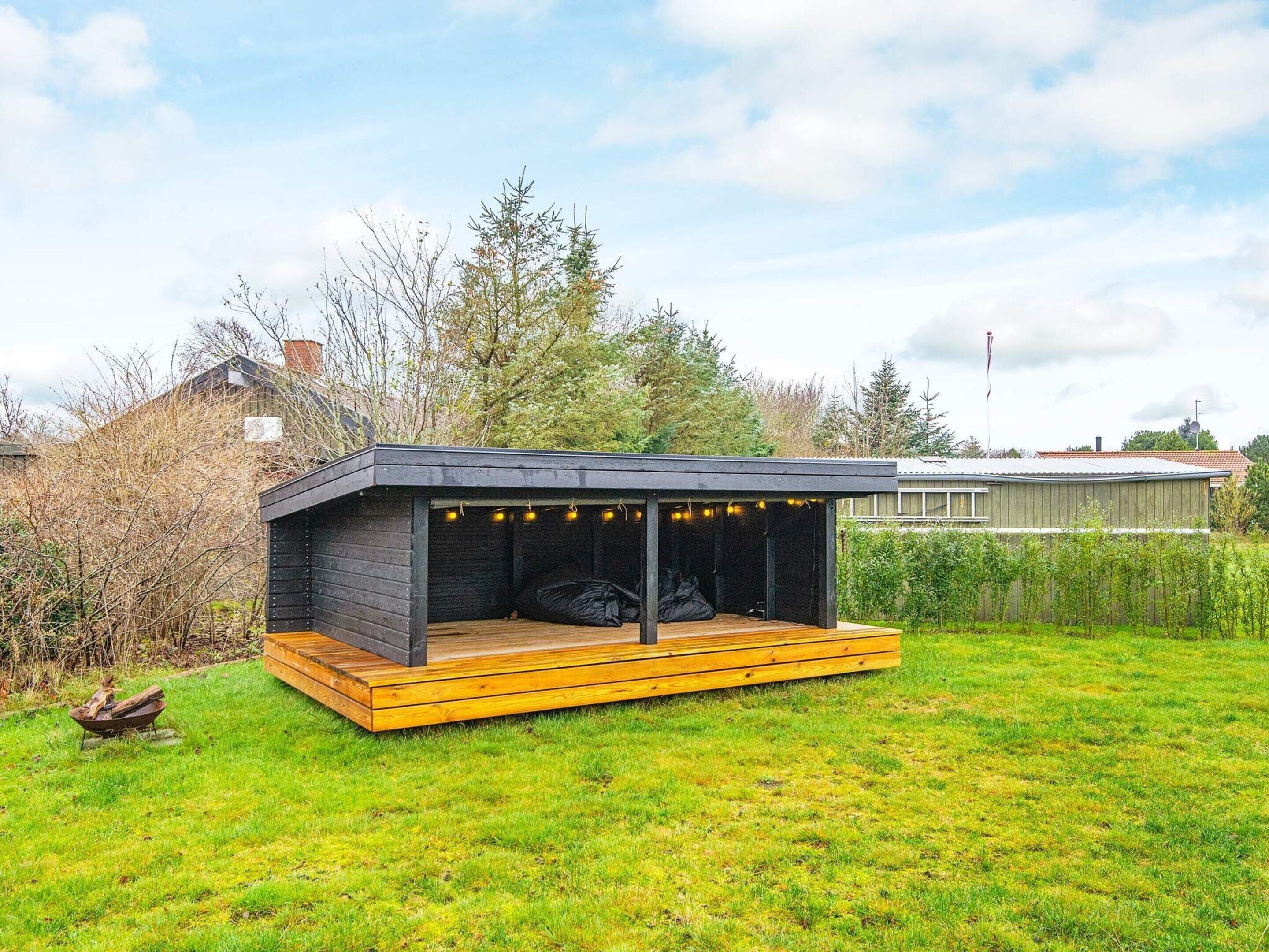 Una estructura moderna al aire libre con terraza de madera y zona de estar cubierta.