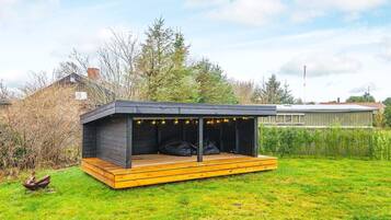 Una estructura moderna al aire libre con terraza de madera y zona de estar cubierta.