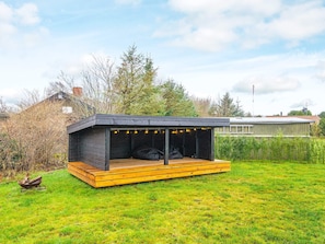 Una estructura moderna al aire libre con terraza de madera y zona de estar cubierta.
