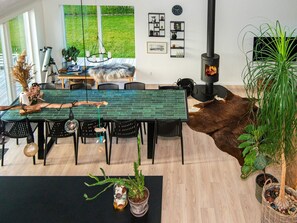 Un comedor moderno con una mesa de ladrillo, sillas negras y un ventanal grande con vistas a un jardín.