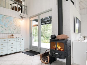 A room with a white dresser, a map on the wall, a black wood-burning stove, and a wicker basket. - 6 Person Holiday Home in Roslev (Roslev)