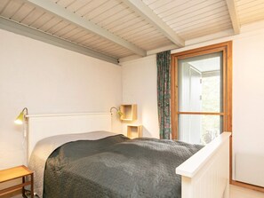 A bedroom with a bed, a bedside lamp, a window with curtains, and a radiator. - 6 Person Holiday Home in Roslev (Roslev)