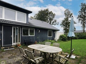 A house with a patio, a round table, and outdoor seating. - 6 Person Holiday Home in Roslev (Roslev)