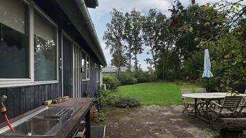 Eine Terrasse mit Tisch, Stühlen, einem Grill und einem Spülbecken.