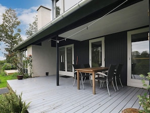 A wooden deck with a table and chairs, a potted plant, and a view of the surrounding greenery. - 6 Person Holiday Home in Roslev (Roslev)
