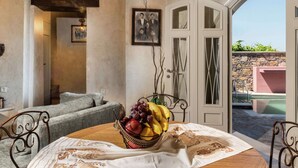 A dining area with a round table, a wicker fruit basket, and a view of the outside.