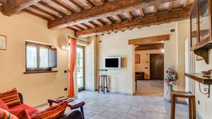A cozy living area with a leather sofa, a wooden coffee table, and a TV mounted on the wall. - Holiday Home in Urbania With Hill Views (Urbania)